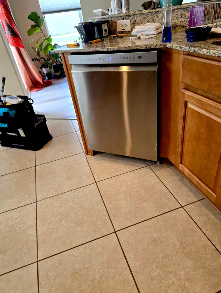 Modern kitchen with stainless steel dishwasher, wood cabinets, granite countertop, and tile flooring